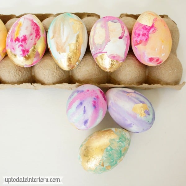 DIY water color and gold leaf easter eggs sitting in an egg box.