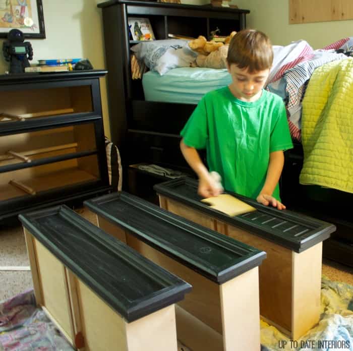 A boy sanding a dresser front to prepare it for an easy dresser update.