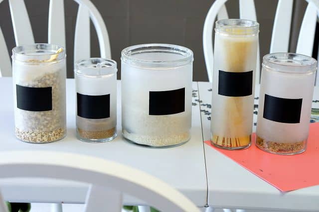 A glass canister set on a white kitchen table with DIY chalkboard paint labels. 