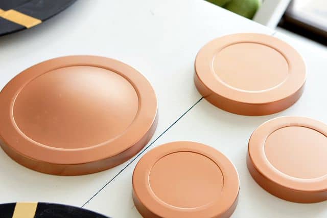 Copper spray painted canister lids laying on a white table.