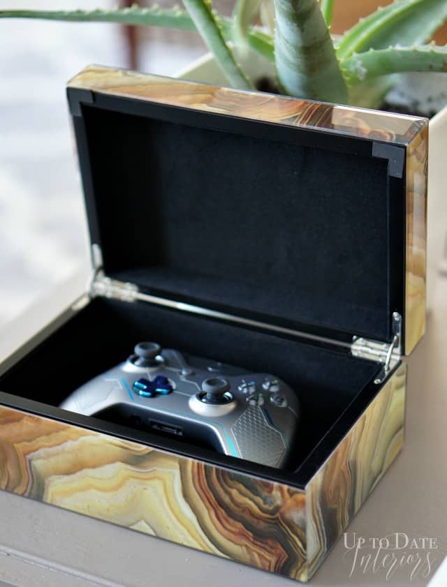 Remote control storage ideas showing a pretty burled wood jewelry box holding a gaming remote. 