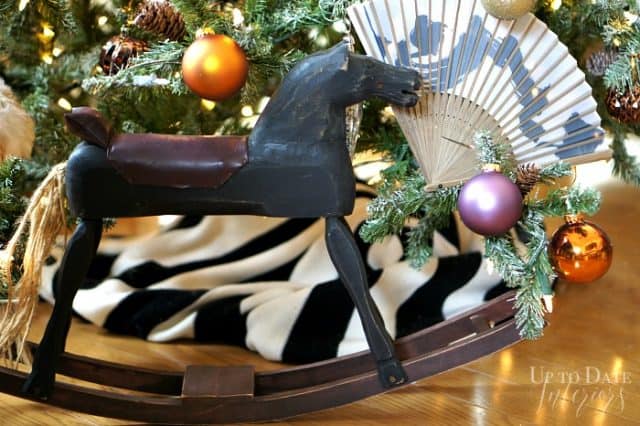 A primitive rocking horse under the Christmas tree with black and white and colorful ornaments. 