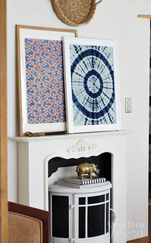 Shibori fabric and washi paper print framed for large art over a white faux mantel with a white stove room heater underneath. 