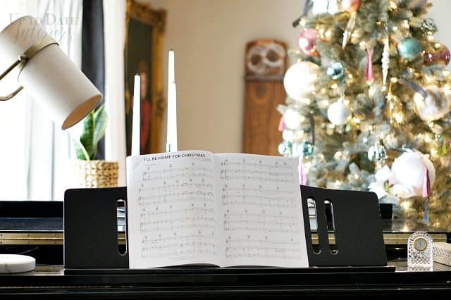 Christmas music on a black grand piano with a Christmas tree in the background. 