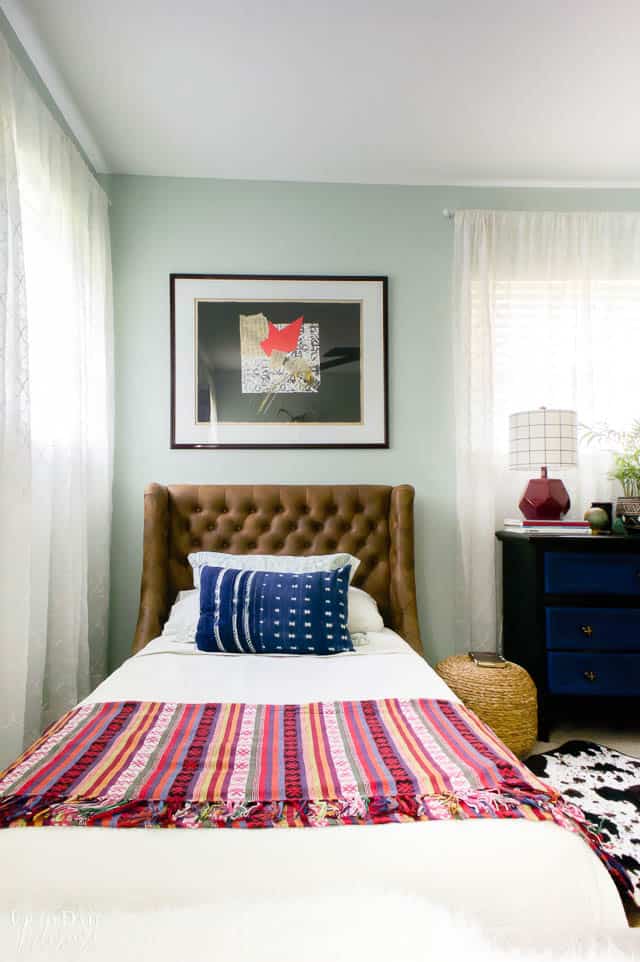 An eclectic teen boy's room with a tufted twin leather headboard, art, and global textiles. 