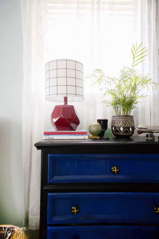 An eclectic teen boy's room with a black and navy painted dresser and colorful decor.
