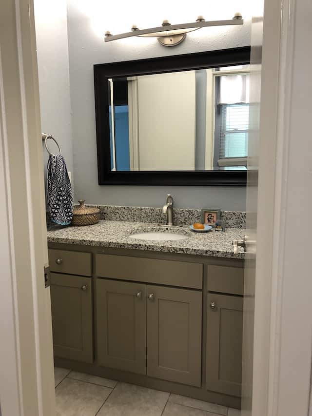 grey bathroom vanity area with grey floors, cabinets, and granite countertop with light blue walls