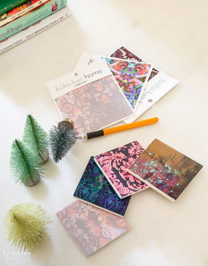 Wallpaper peel and stick samples are on a table with tile coasters DIY. 