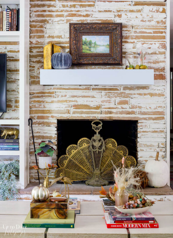 Eclectic Home Tour For Fall Watermark 700 23 fireplace with brass screen and oil painting, coffee table with eclectic decor. 