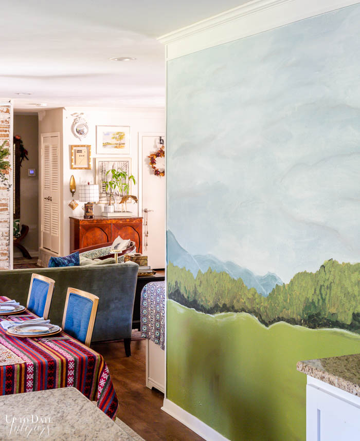 A hand-painted abstract landscape mural is in a small dining area featuring eclectic and colorful decor.
