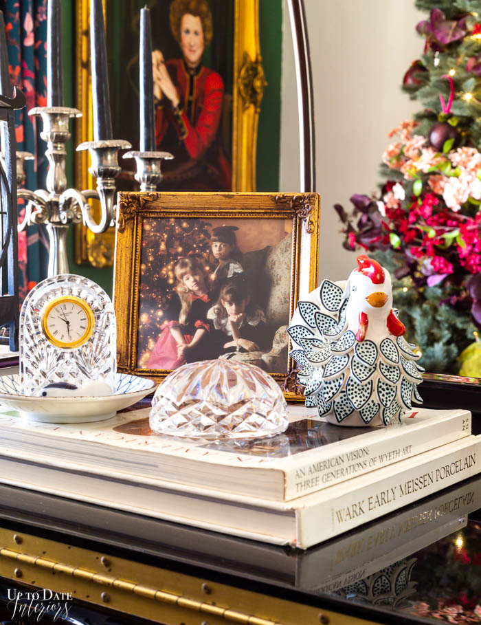 A Christmas vignette on a grand piano featuring crystal, books, and a picture. 