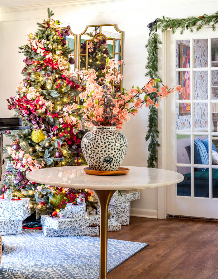 A gorgeous floral Christmas tree is in the corner of a room with a white tulip marble table and matching floral arrangement. 