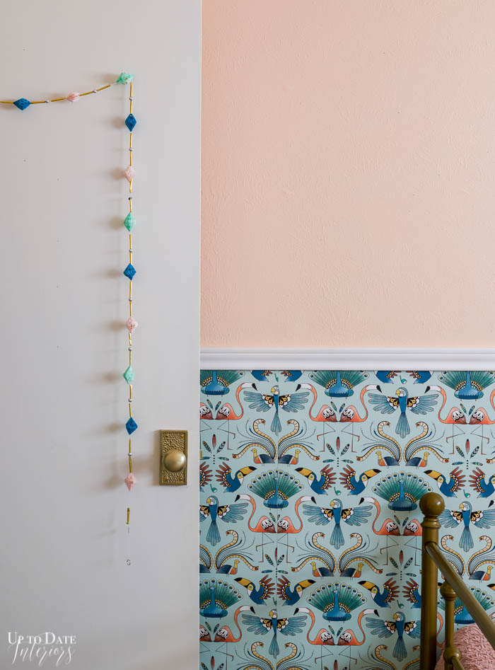 Cute tinsel and paper garland hang on a girl's bedroom door with view of bird wallpaper and pink walls. 