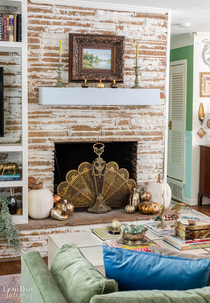 A neutral Fall fireplace pops next to a blue and green painted hallway. 