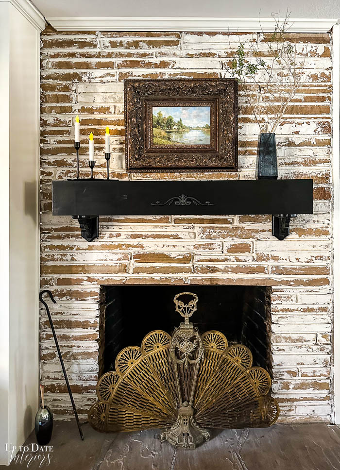 A german smear fireplace is updated with a floating mantel makeover using corbels, wood embellishment and black paint.  A brass peacock screen completes the look.